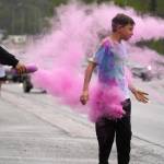 Attendees brave purple colored powder during a color run as part of the opening night of the Levitt AMP Soldotna Music Series along the Sterling Highway in Soldotna, Alaska, on Wednesday, June 5, 2024. (Jake Dye/Peninsula Clarion)