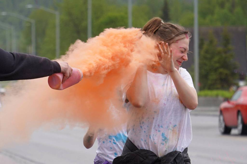 Attendees brave orange colored powder during a color run as part of the opening night of the Levitt AMP Soldotna Music Series along the Sterling Highway in Soldotna, Alaska, on Wednesday, June 5, 2024. (Jake Dye/Peninsula Clarion)