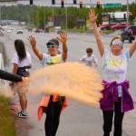 Attendees brave orange colored powder during a color run as part of the opening night of the Levitt AMP Soldotna Music Series along the Sterling Highway in Soldotna, Alaska, on Wednesday, June 5, 2024. (Jake Dye/Peninsula Clarion)