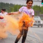 Emily Musgrove emerges from a cloud of orange powder during a color run as part of the opening night of the Levitt AMP Soldotna Music Series along the Sterling Highway in Soldotna, Alaska, on Wednesday, June 5, 2024. (Jake Dye/Peninsula Clarion)