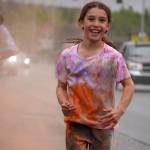 Emily Musgrove emerges from a cloud of orange powder during a color run as part of the opening night of the Levitt AMP Soldotna Music Series along the Sterling Highway in Soldotna, Alaska, on Wednesday, June 5, 2024. (Jake Dye/Peninsula Clarion)