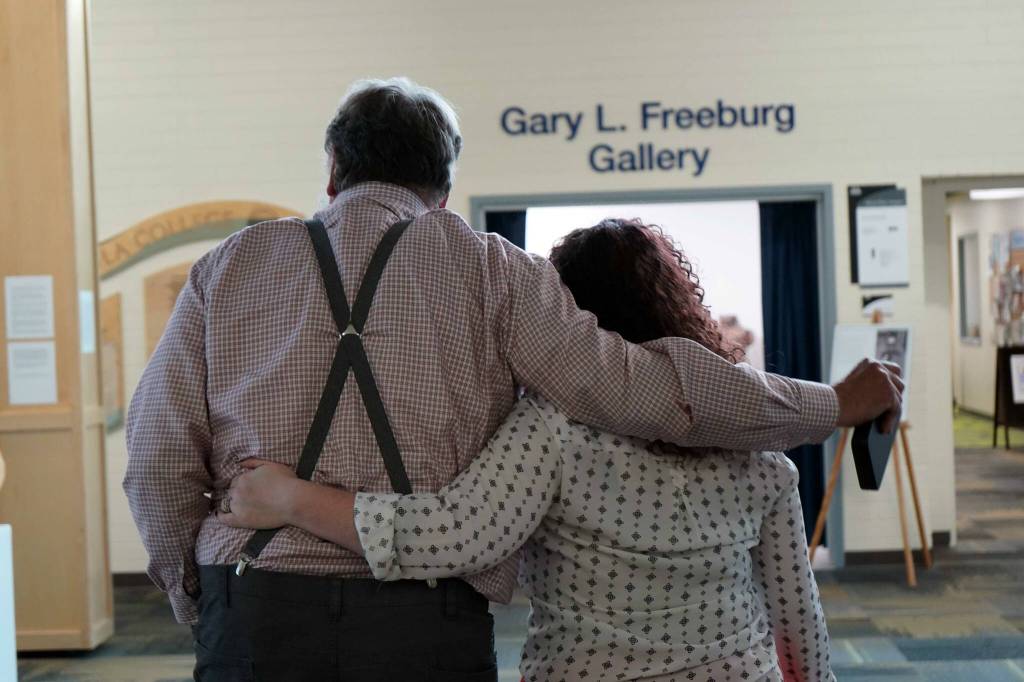 Tom Dalrymple and Brandi Kerley share an embrace before the opening of a memorial art gallery for Kenai Peninsula College Associate Professor of Art Cambid-J Cam Choy at Kenai Peninsula College in Soldotna, Alaska, on Friday, Sept. 13, 2024. (Jake Dye/Peninsula Clarion)
