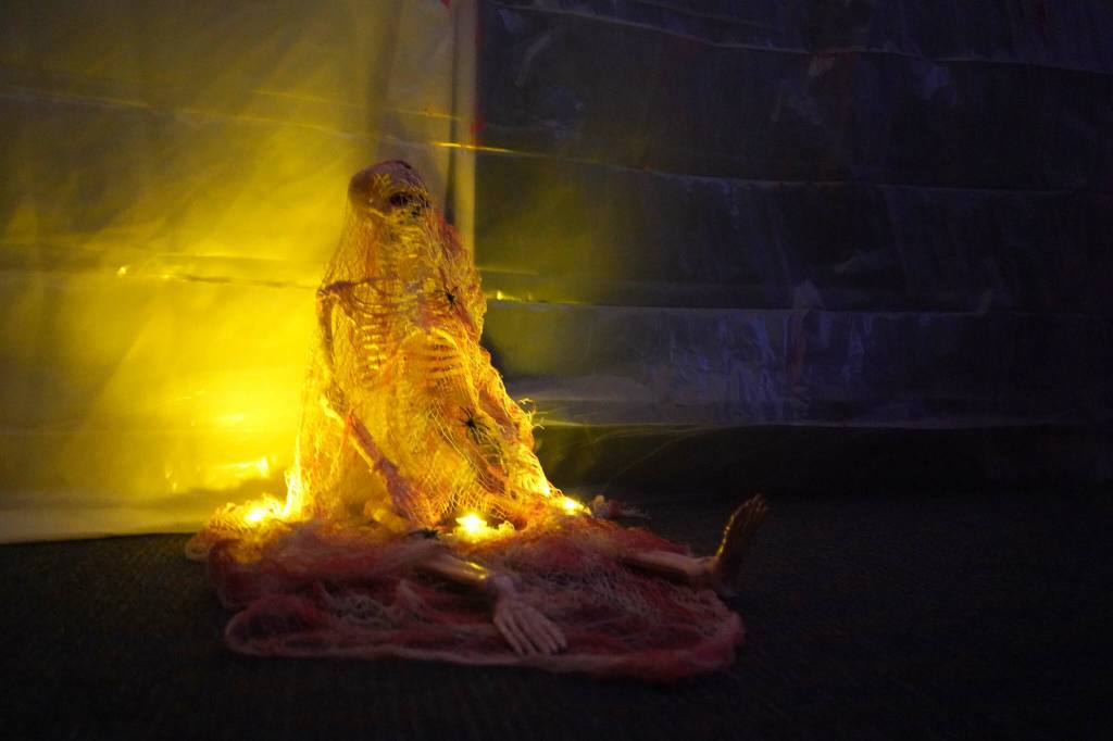 A skeleton wrapped in cobwebs rests on the floor of the Haunted Chamber at the Kenai Chamber of Commerce and Visitor Center in Kenai, Alaska, on Friday, Oct. 18, 2024. (Jake Dye/Peninsula Clarion)
