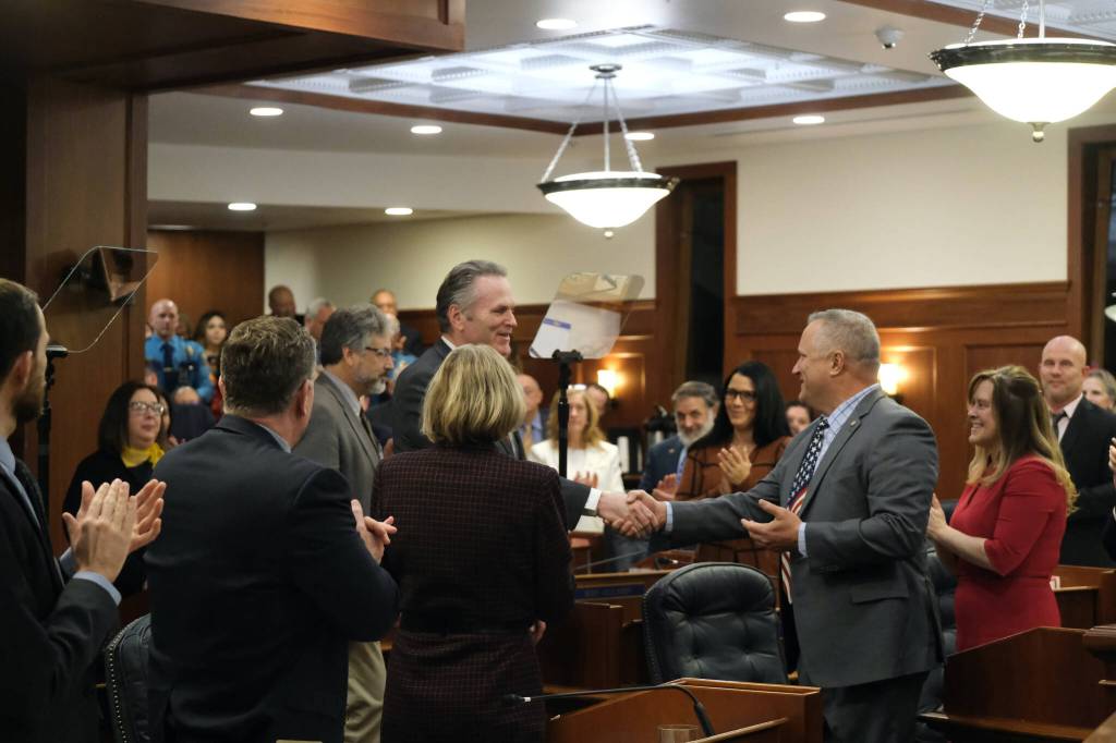 Republican Gov. Mike Dunleavy, center, shakes hands with Senate Minority Leader Mike Shower, a Wasilla Republican, right, before delivering his State of the State speech Tuesday, Jan. 28, 2025, at the Alaska State Capitol. (Klas Stolpe/Juneau Empire)