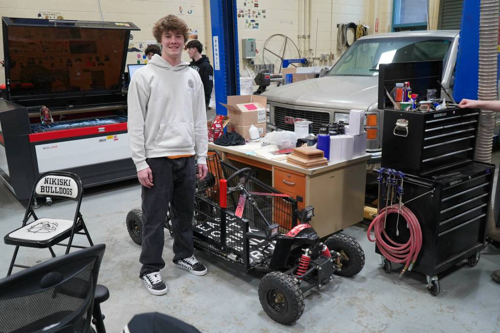 Gavin Ley stands with the Go-Shopping Kart he designed and built in his career and technical education courses at Nikiski Middle/High School in Nikiski, Alaska, on Tuesday, Feb. 11, 2025. (Jake Dye/Peninsula Clarion)