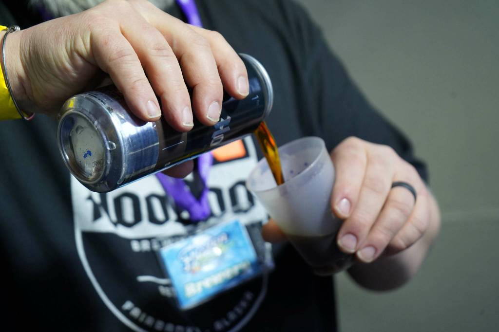 A brewer from HooDoo Brewing Company fills a cup for an attendee at the 10th Annual Frozen River Fest in Soldotna, Alaska, on Saturday, Feb. 15, 2025. (Jake Dye/Peninsula Clarion)
