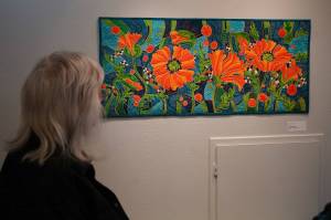 Attendees admire Neon Poppies by Chelline Larsen during the opening reception for Infusion at the Kenai Art Center in Kenai, Alaska, on Friday, March 7, 2025. (Jake Dye/Peninsula Clarion)