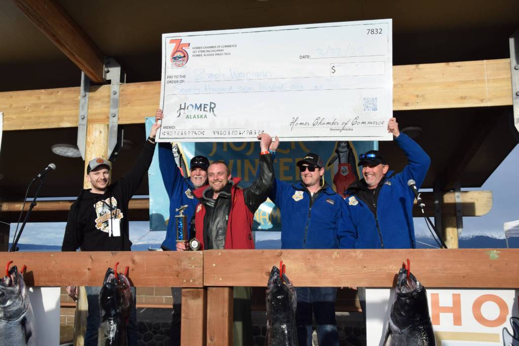 Tournament staff and volunteers help Zach Weimann (center), tournament champion, hold up a check displaying his winnings during the 2025 Homer Winter King Salmon Tournament on Saturday, March 22, 2025, at the Deep Water Dock on the Homer Spit in Homer, Alaska. (Delcenia Cosman/Homer News)