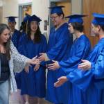 Katie Hunter high fives Kenai Alternative High Schools graduates only moments before their commencement ceremony in the schools gym in Kenai, Alaska, on Wednesday, May 22, 2025. (Jake Dye/Peninsula Clarion)