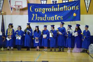 Kenai Alternative High School graduates stand with their diplomas at the conclusion of their commencement ceremony in the schools gym in Kenai, Alaska, on Wednesday, May 22, 2025. (Jake Dye/Peninsula Clarion)