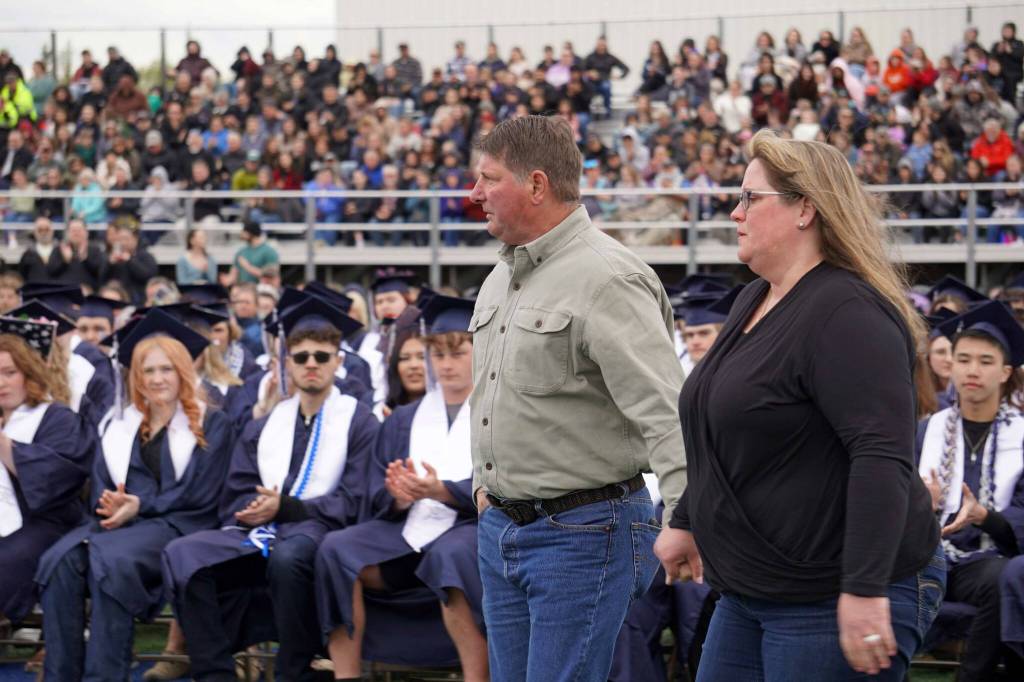 The parents of Tucker Challans, a Soldotna High School student who died in March, advance to receive an honorary diploma for their son on the schools football field in Soldotna, Alaska, on Wednesday, May 21, 2025. (Jake Dye/Peninsula Clarion)