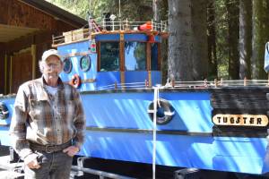 Larry Bernbeck poses for a photo with Tugster on Thursday, June 5, 2025 in Homer, Alaska. (Chloe Pleznac/Homer News)
