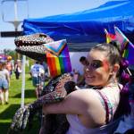 Nala Johnson hoists a velociraptor carrying a progress flag during the Saturday Market at the Goods in Soldotna, Alaska, on Saturday, June 14, 2025. (Jake Dye/Peninsula Clarion)