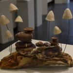 Clay mushrooms sit on a log at the Kenai Potters Guild exhibit, River, hosted by the Kenai Art Center. (Jonas Oyoumick/Peninsula Clarion)