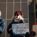 Larri Spengler holds a sign reading PFDs dont work if the ocean is polluted during an anti-LNG pipeline protest led by the Juneau-Douglas High School: Yadaa.at Kalé chapter of Alaska Youth for Environmental Action outside the Alaska State Capitol on Saturday, Jan. 24<ins>, 2026</ins>.