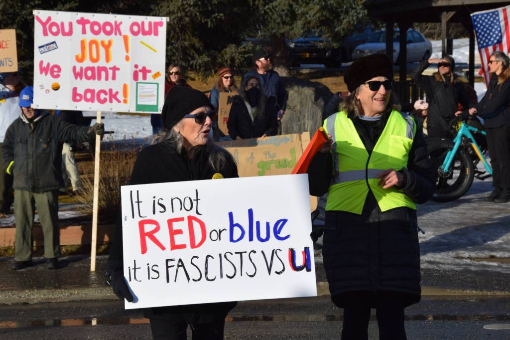 A protester crosses Pioneer Avenue carrying a sign that reads, It is not red or blue, it is fascists vs u, during the ICE OUT demonstration on Sunday, Feb. 1, 2026, at WKFL Park in Homer, Alaska. (Delcenia Cosman/Homer News)