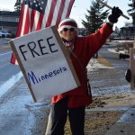 Poppy Benson carries an American flag and a Free Minnesota sign during the ICE OUT demonstration on Sunday, Feb. 1, 2026, at WKFL Park in Homer, Alaska. (Delcenia Cosman/Homer News)